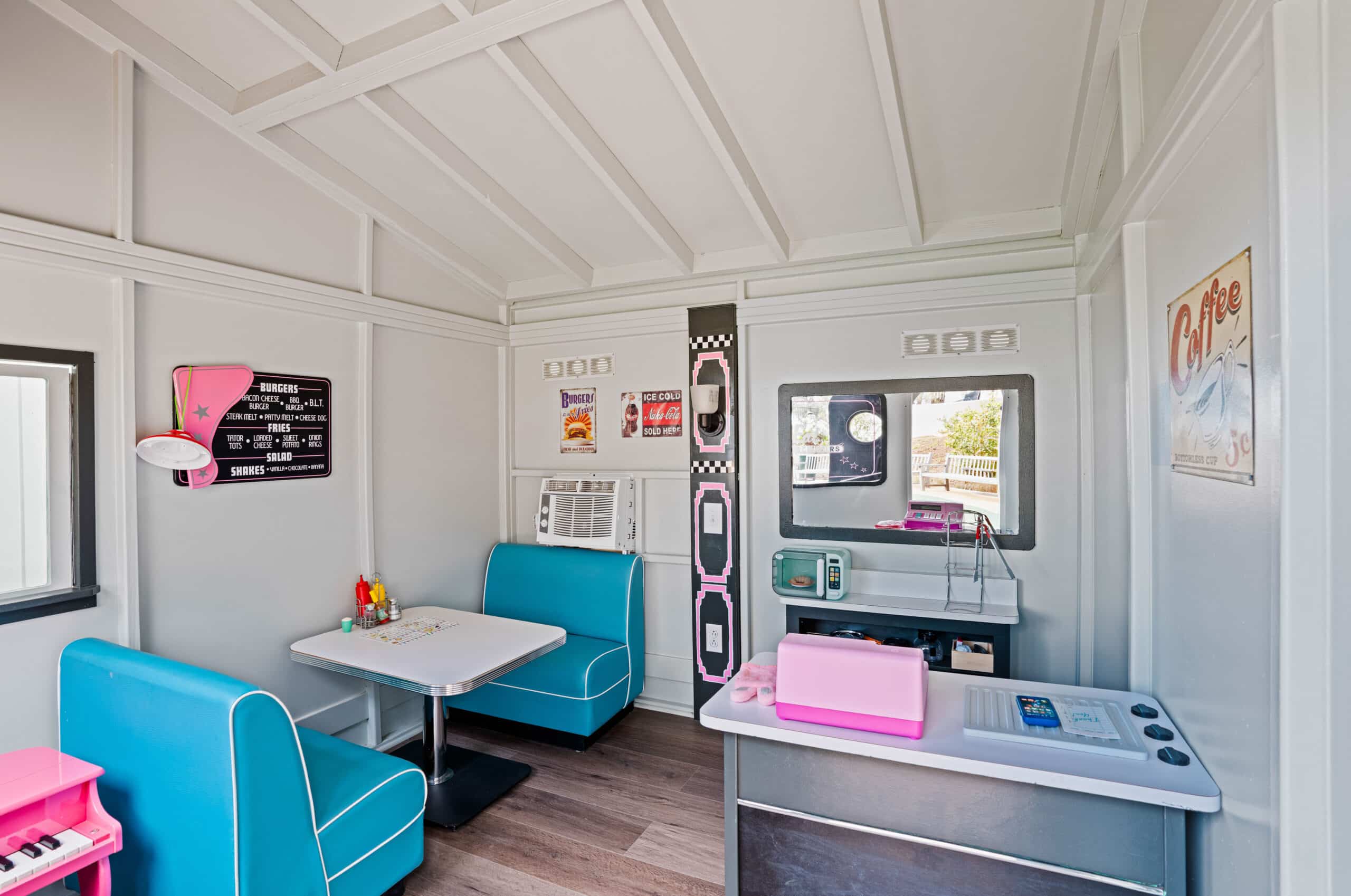 Duffy's Diner offers a luxury nostalgic vibe with its retro-style interior featuring turquoise booths, vintage signage, classic menu displays on the walls, playful toy items on tables, and light wood flooring.