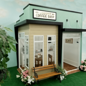 The Uptown Coffee Shop is a miniature playhouse model designed for a imaginative play area. It features a custom sign identifying the "shop" and a custom menu sign. It also showcases a hand-built child-size counter.