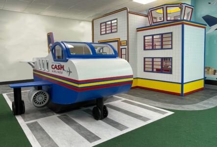 Airplane play house in front of airport terminal and tower