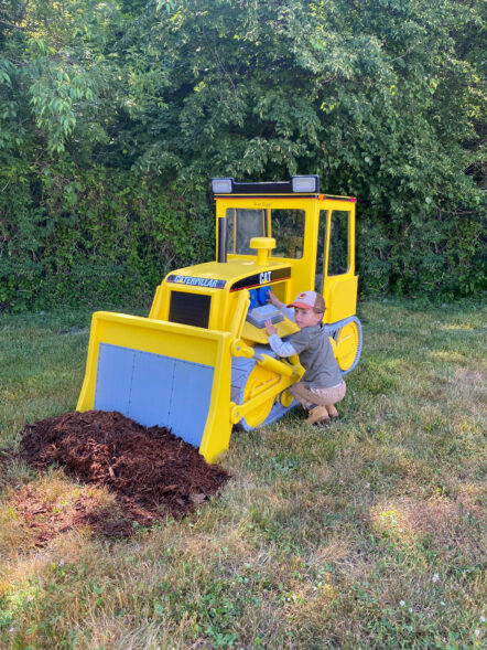 Side view of Little Buddy Bulldozer with little boy playing with equipment under the hood