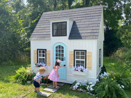Little girl and boy opening the door of Hopscotch Hideaway playhouse