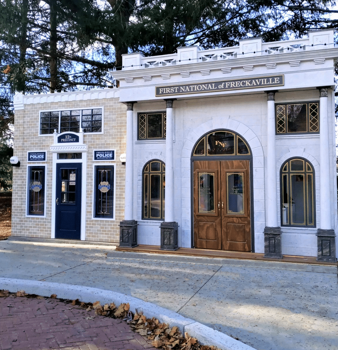 Grand playhouse structures built for an outdoor play village and include a bank and a police station.