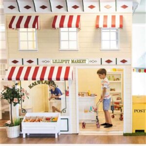 Lilliput's Grocery Market playhouse pictured with children playing inside, as part of a larger play town found in a play cafe.