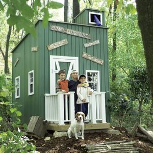 Boys and their dog stand proudly in front of a boy clubhouse playhouse.