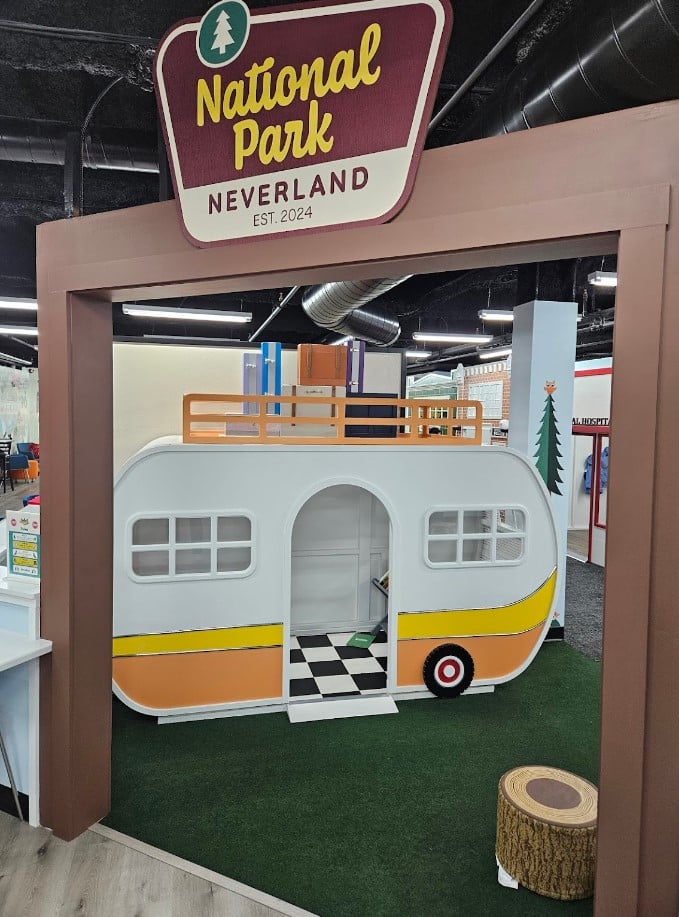 Children's playhouse Camper in custom colors shown under a entrance sign to a children's commercial play center.