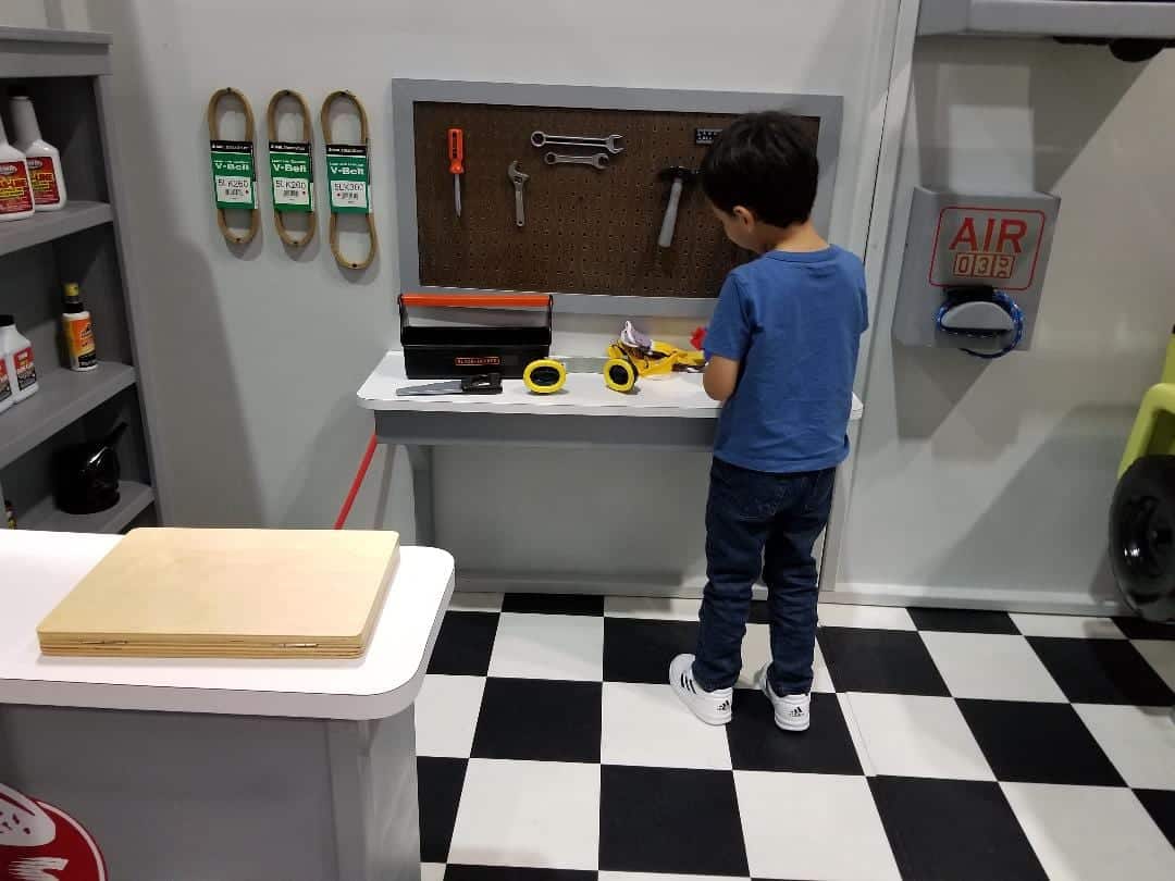 Child playing on the workbench of Lilliput's Uptown Service Station playhouse.