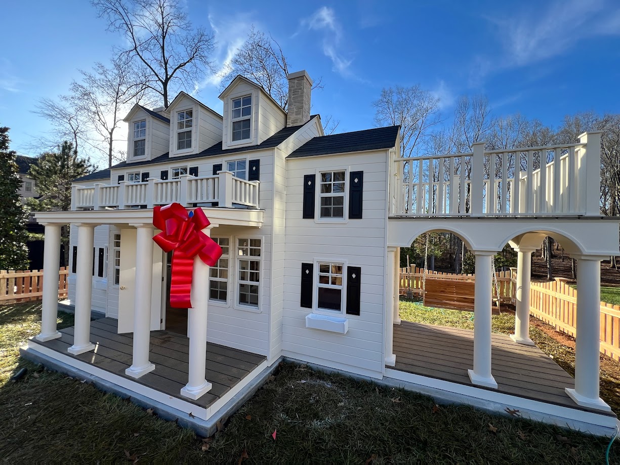 Large luxury custom play house, with a porch swing and large red bow.