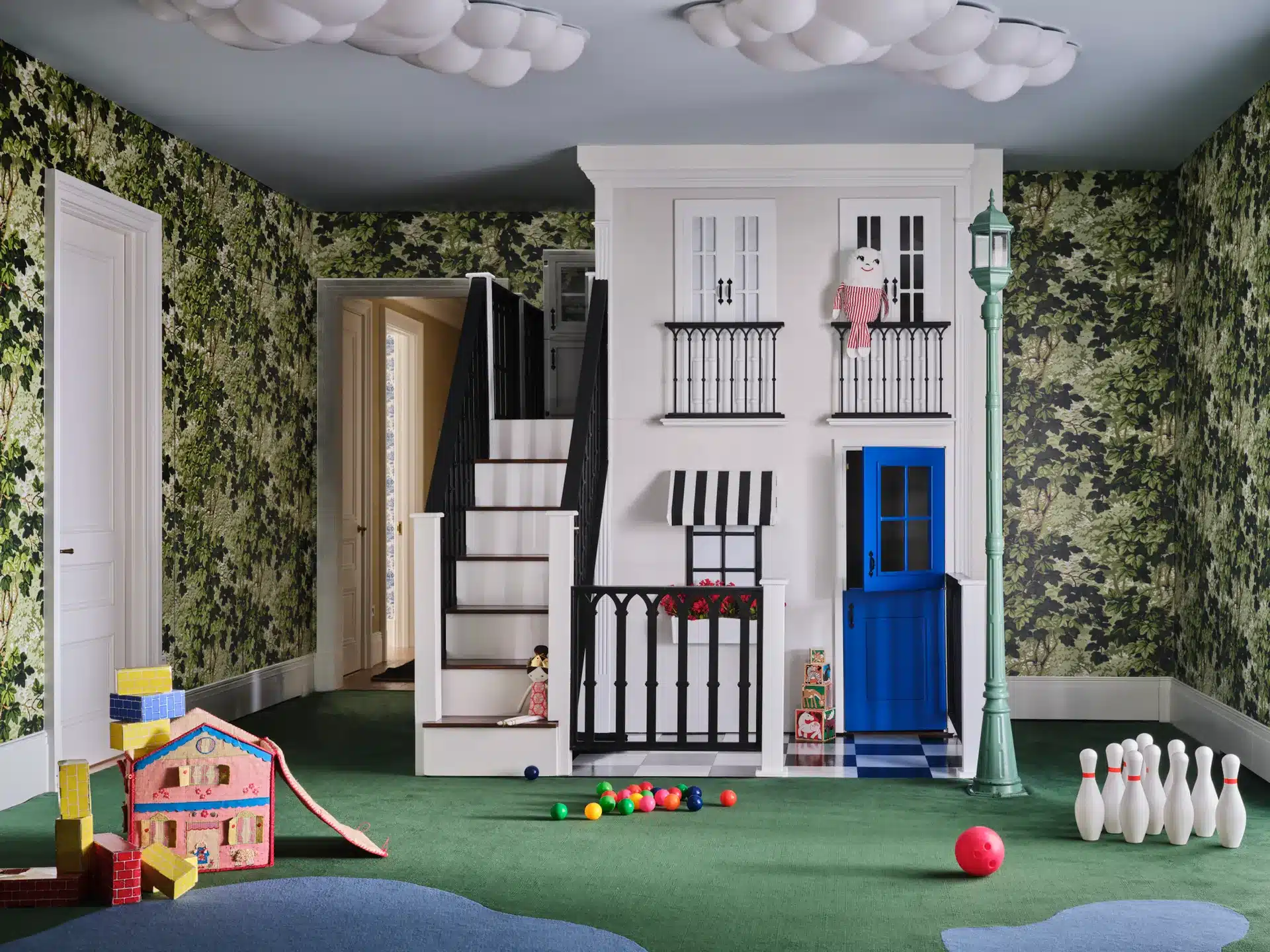 A lovely indoor playroom playhouse with steps leading to a second level. The playhouse boasts a window with awning and a decorative railing entrance.