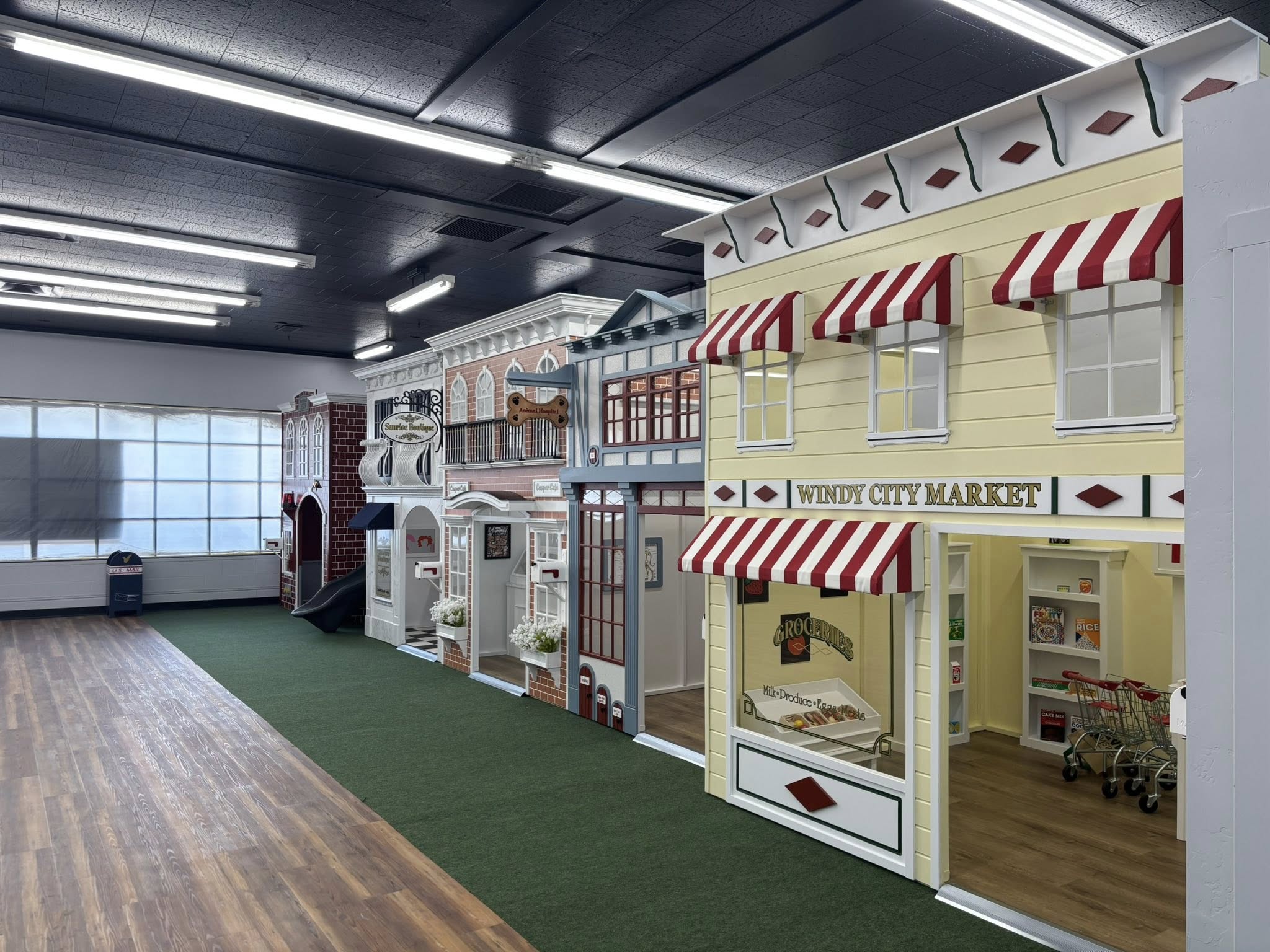 Village of play houses built for imaginative play in different themes, including a market, animal hospital, and cafe