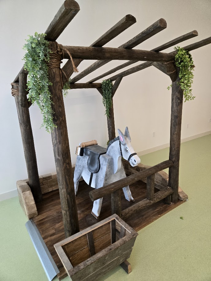 A custom child sized stall, with a small donkey inside outfitted with a saddle. It was built for children to interact with.