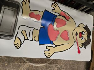 A pretend play operation table for children, with openings for different pretend organ parts, and a thermometer in the characters mouth.