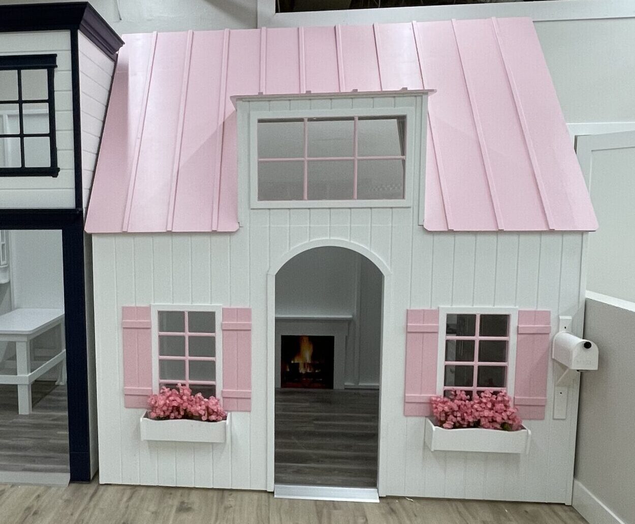 Children’s play area with two playhouses: one styled as a medical center with a red cross, and the other as a pink and white house with flower boxes under the windows.